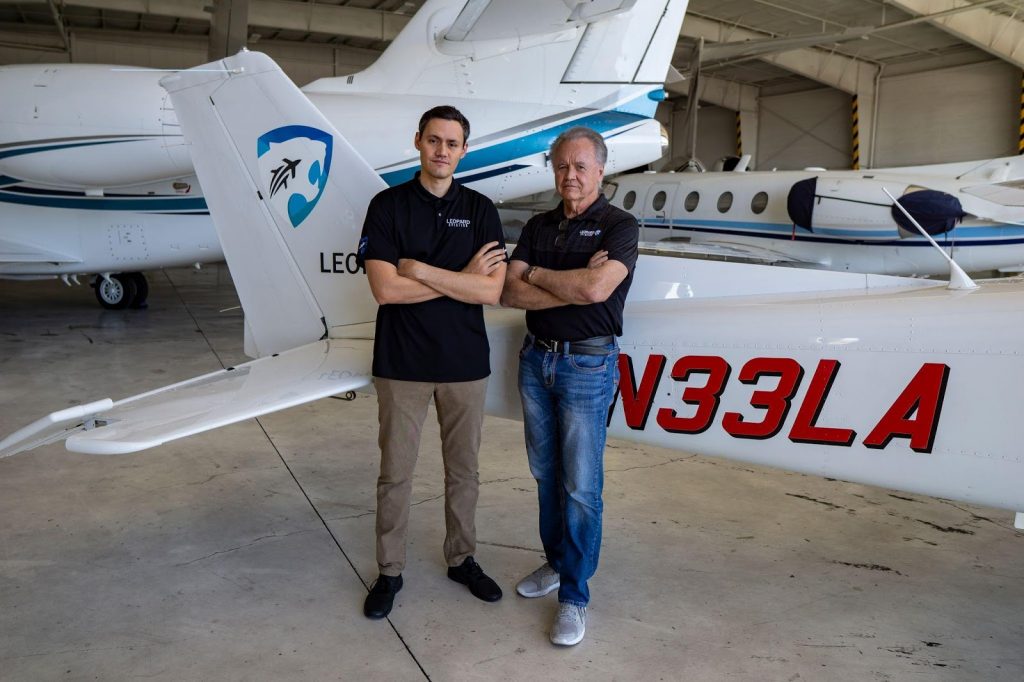 Two men standing in front of a plane in a hangar