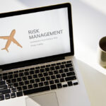 Image of laptop with airplane image and risk management sign.