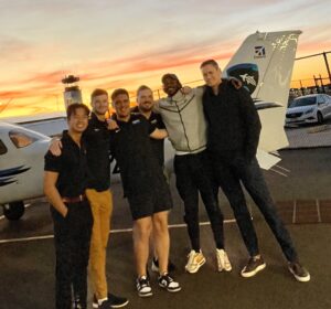 Image of flight school students next to a Cessna as the sun is setting on the runway