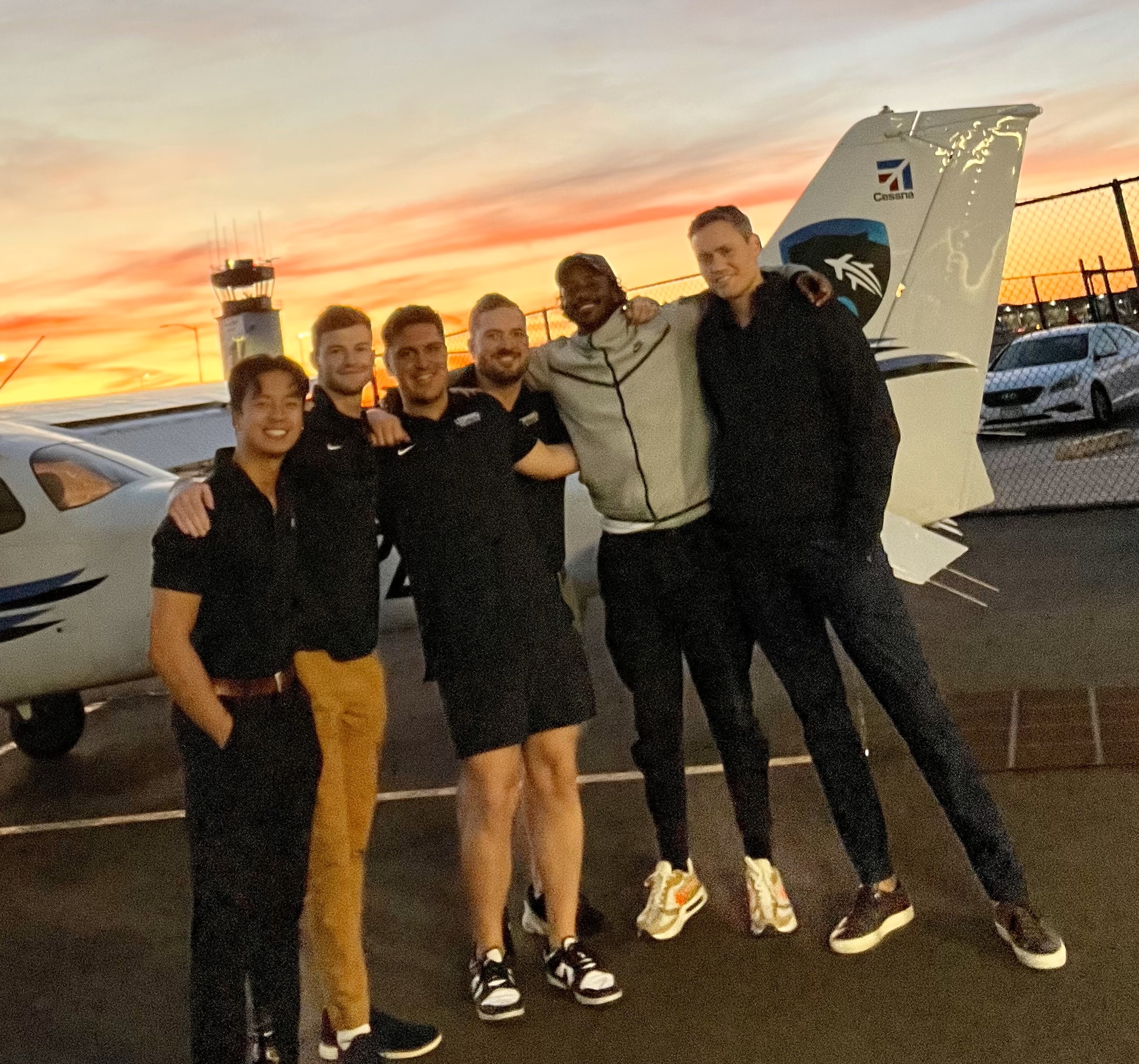 Image of flight school students next to a Cessna as the sun is setting on the runway